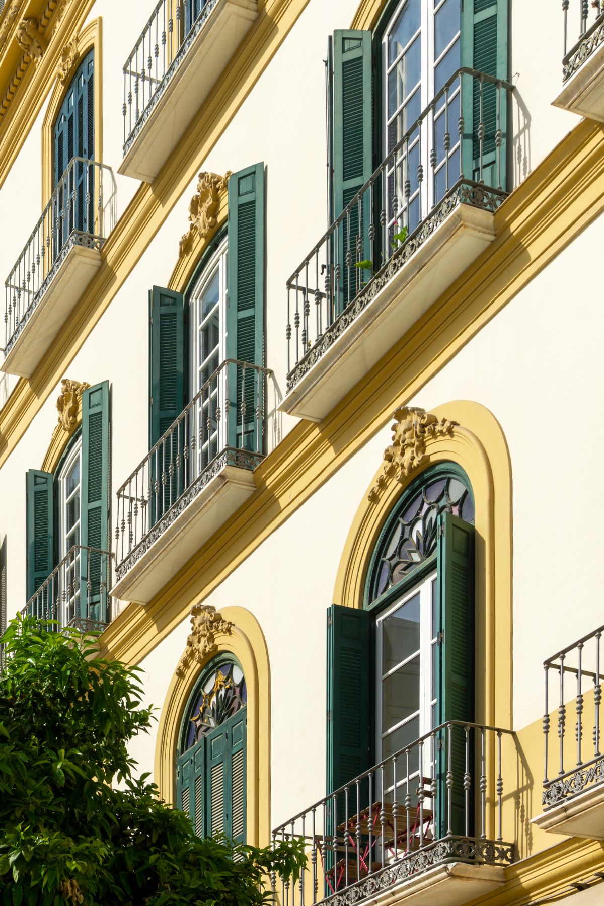 Fachada de un edificio de viviendas con balcones de forja y persianas de madera a media tarde